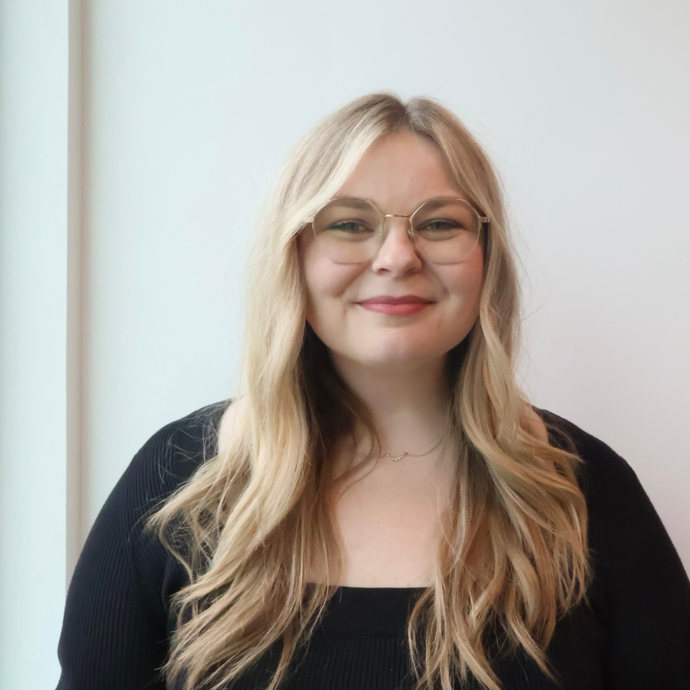 Delaniepic-cropped Staff member smiles at camera, wearing glasses with long blond hair.