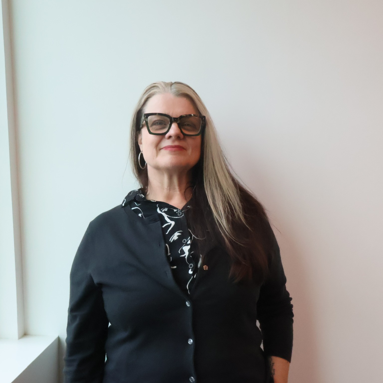 carapic-cropped Staff member wearing black-rimmed glasses smiles into camera.