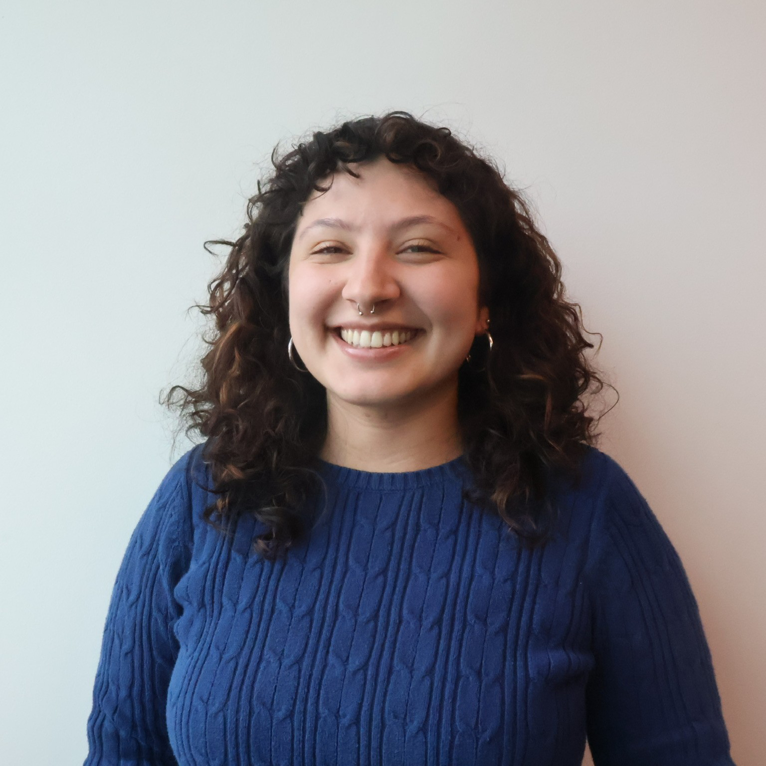 sarapic-cropped Staff member wearing a cable-knit navy sweater smiles into the camera.